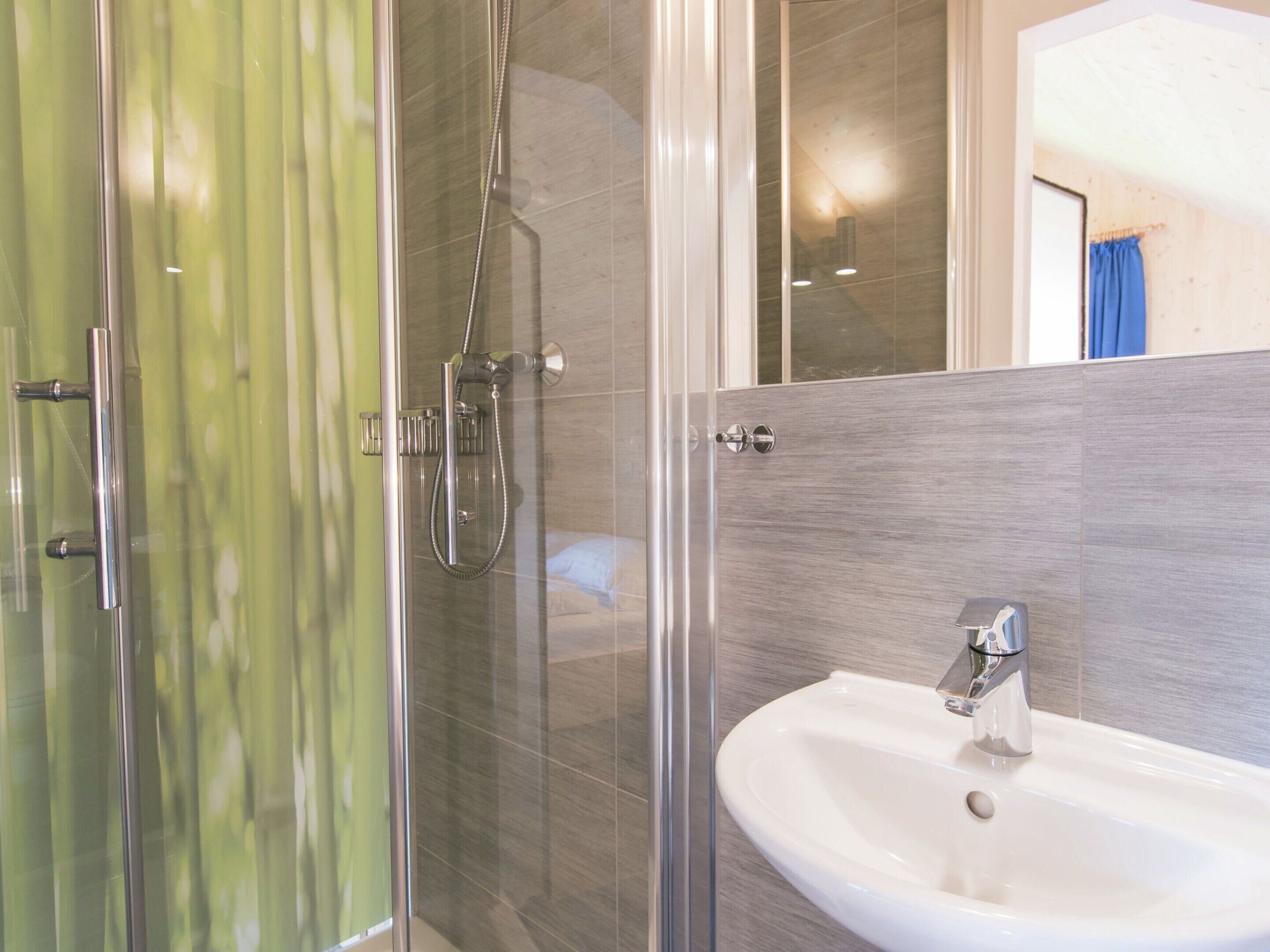 Un baño moderno con cabina de ducha de vidrio, un lavabo blanco y un espejo.
