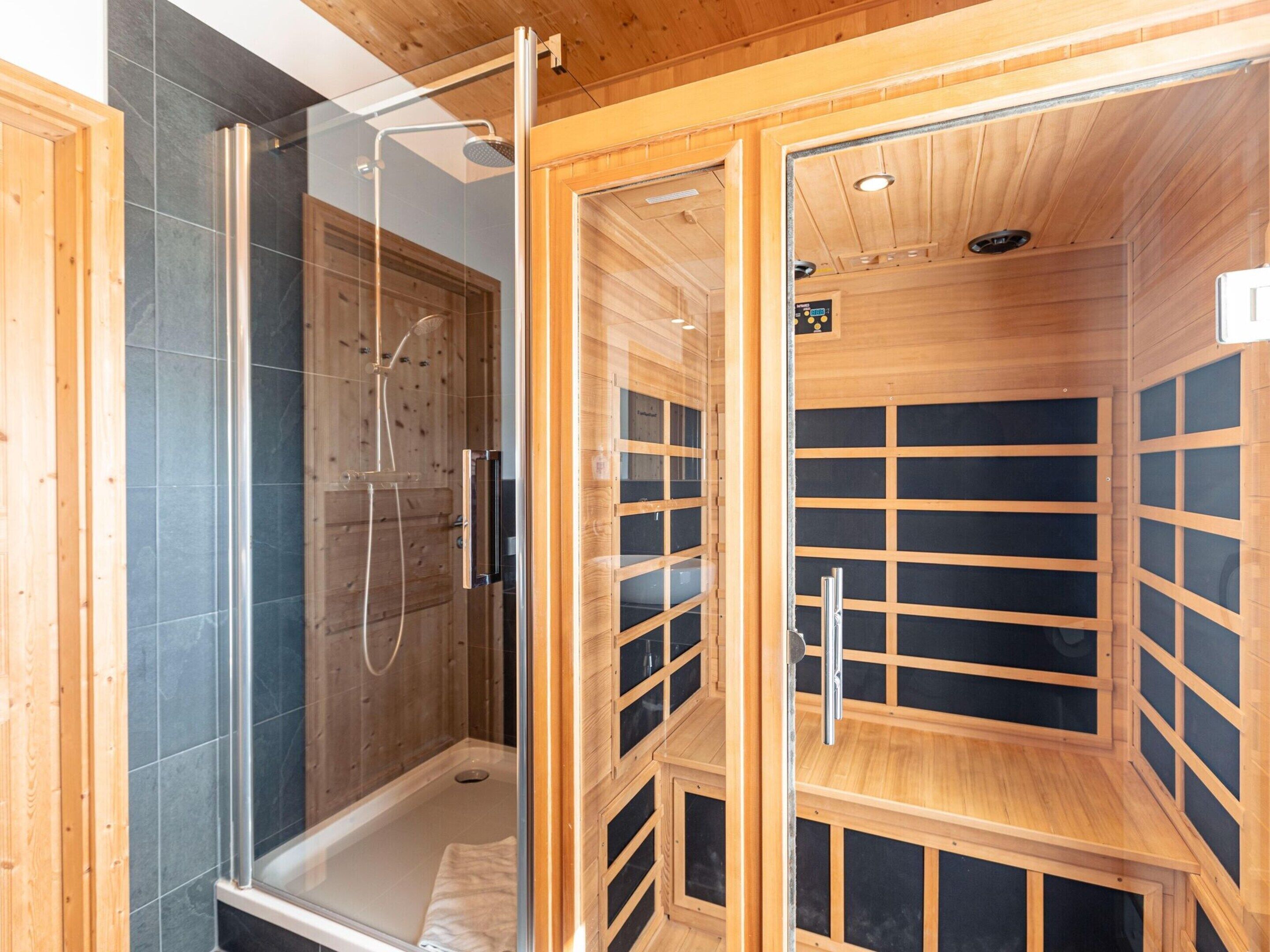 Una sauna con recinto de vidrio, zona de ducha separada e interior de madera.
