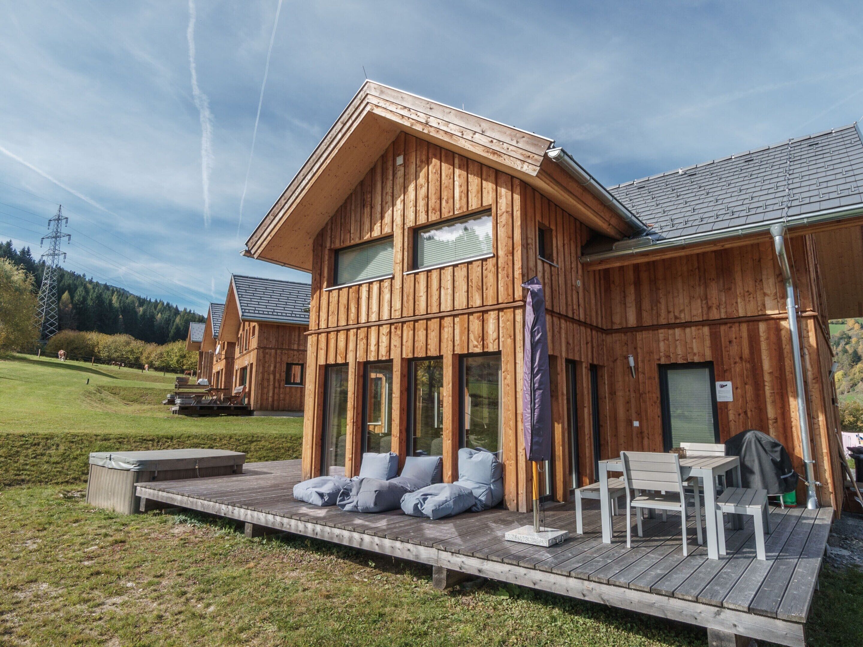 A wooden cabin with a deck, outdoor seating, and a view of the surrounding landscape.