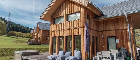 Una cabaña de madera con un porche, mobiliario exterior y vistas del paisaje circundante.