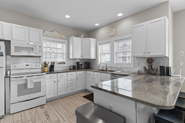 A modern kitchen with white cabinetry, a granite countertop, and a built-in oven.