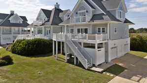 A large, multi-story house with a covered porch and a staircase leading to the upper level. - Aqua Vista #174 - Private Hot Tub, Community Pool, Dog Friendly! (North Topsail Beach)
