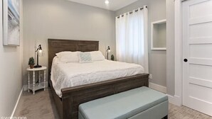 A bedroom with a bed, bedside tables, a bench, and a door. - Newer luxury cottage with hot tub; walking distance to town and beach (New Buffalo)
