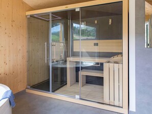 A modern bathroom with a glass shower enclosure, wooden flooring, and a visible outdoor view. - Majestic Chalet With Sauna (Sankt Georgen am Kreischberg)