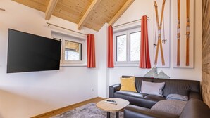 A modern living room with a flat-screen TV, a leather sofa, and a wooden ceiling. - Inviting Chalet on the Ski-slope (Stadl-Predlitz)