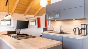 A modern kitchen with a wooden ceiling, grey cabinets, a built-in stove, and a large window with curtains. - Inviting Chalet on the Ski-slope (Stadl-Predlitz)