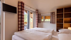 A bedroom with a bed, a TV, a window with curtains, and a wooden shelf. - Spacious Apartment With Terrace (Stadl-Predlitz)