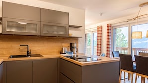 A modern kitchen with a central island, built-in cabinets, and a view to a balcony. - Spacious Apartment With Terrace (Stadl-Predlitz)