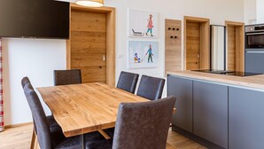 A modern kitchen with a wooden dining table, grey cabinets, and a built-in oven. - Spacious Apartment With Terrace (Stadl-Predlitz)