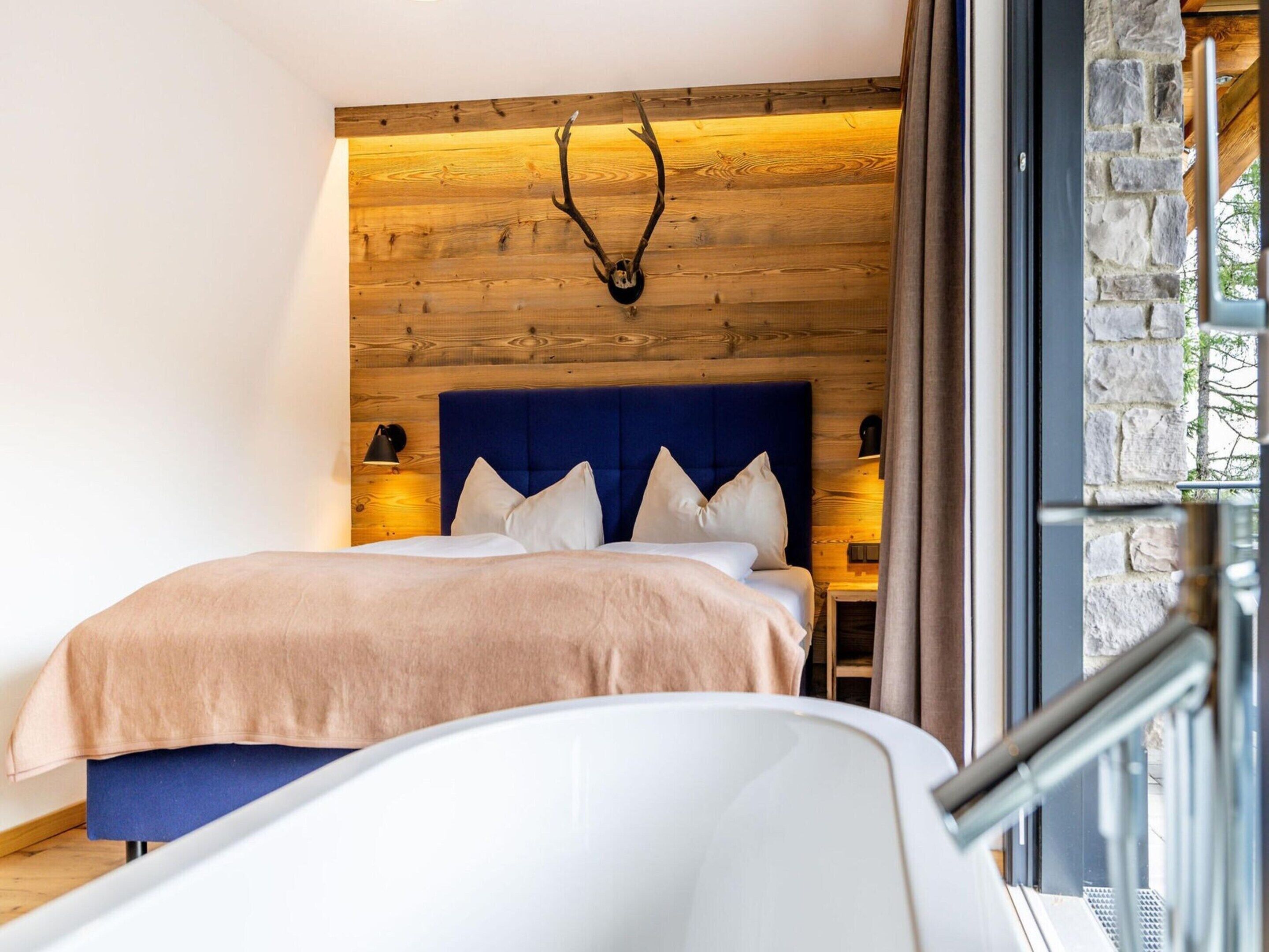 A modern bedroom with a wooden wall, a blue headboard, and a bed with white bedding.