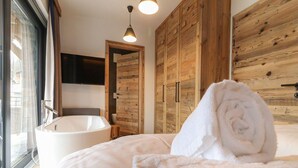 A modern bathroom with a freestanding bathtub, wooden paneling, and a large mirror. - Attractive Chalet on the Ski-slopes (Stadl-Predlitz)