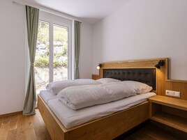 Un dormitorio con cama de madera, mesita de noche y ventana con cortinas.