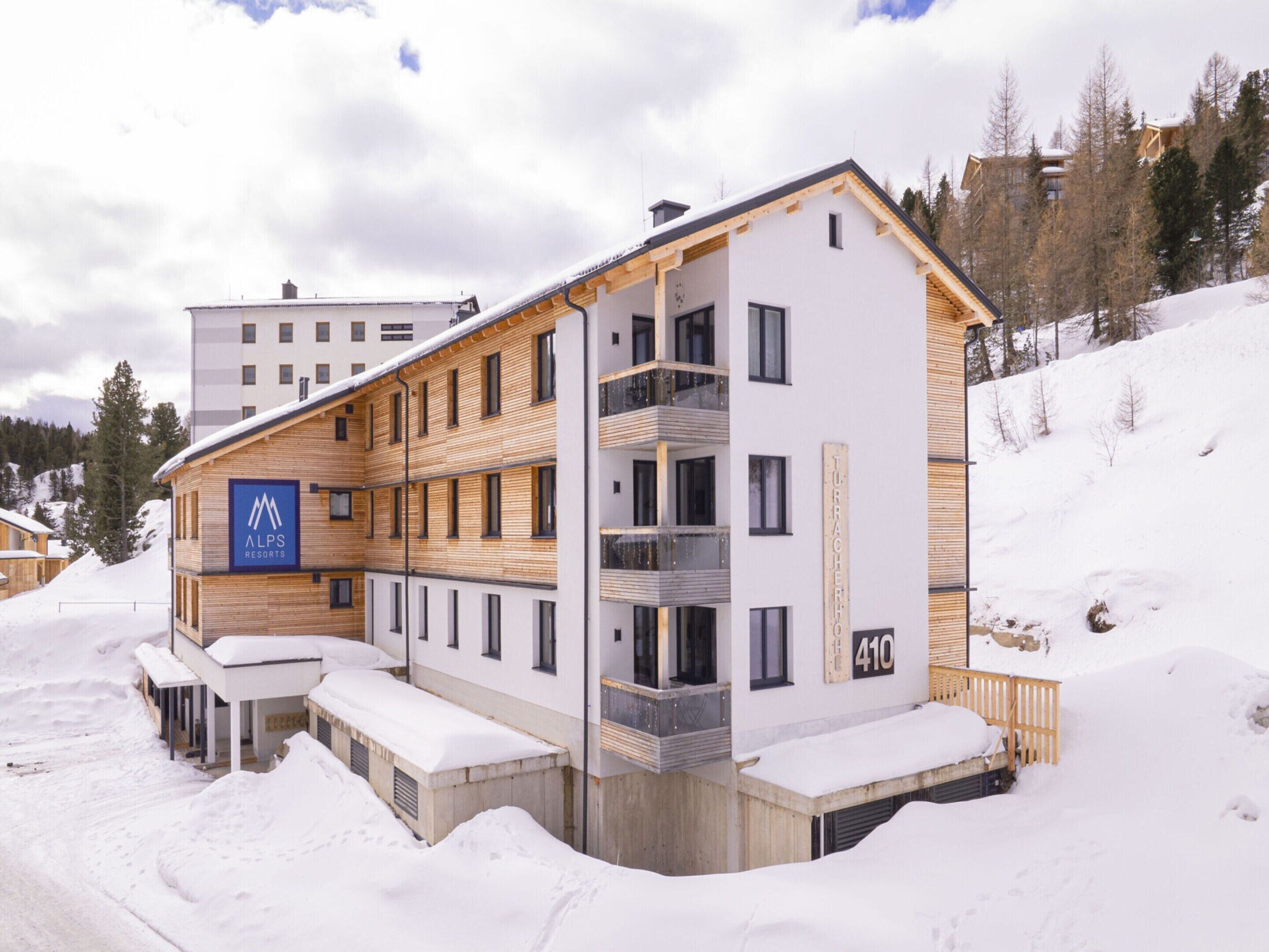 A modern multi-story building with a sign reading "Alps Resorts" and a number "410".
