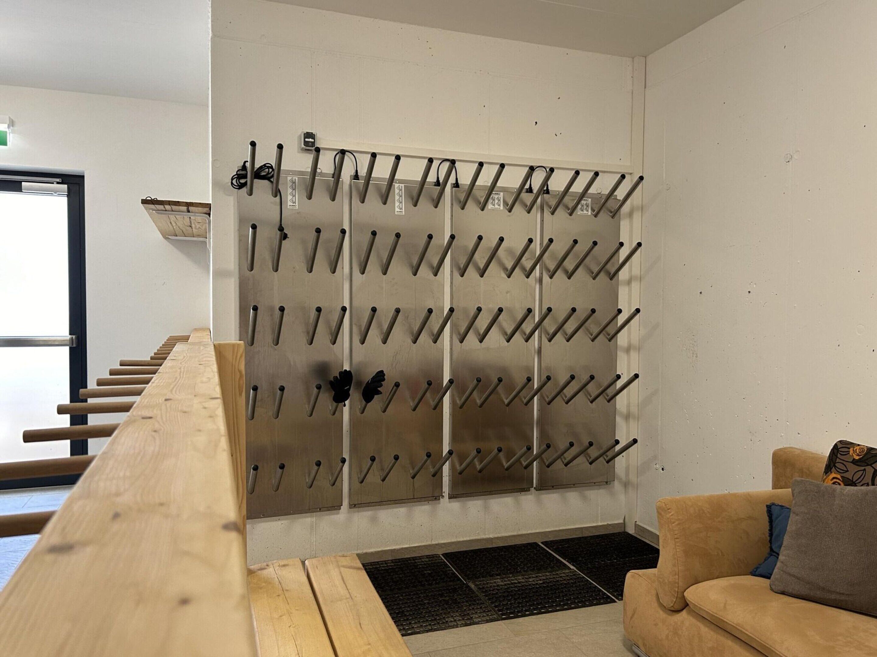 Una habitación con un banco de madera, un sofá y un perchero con ganchos.
