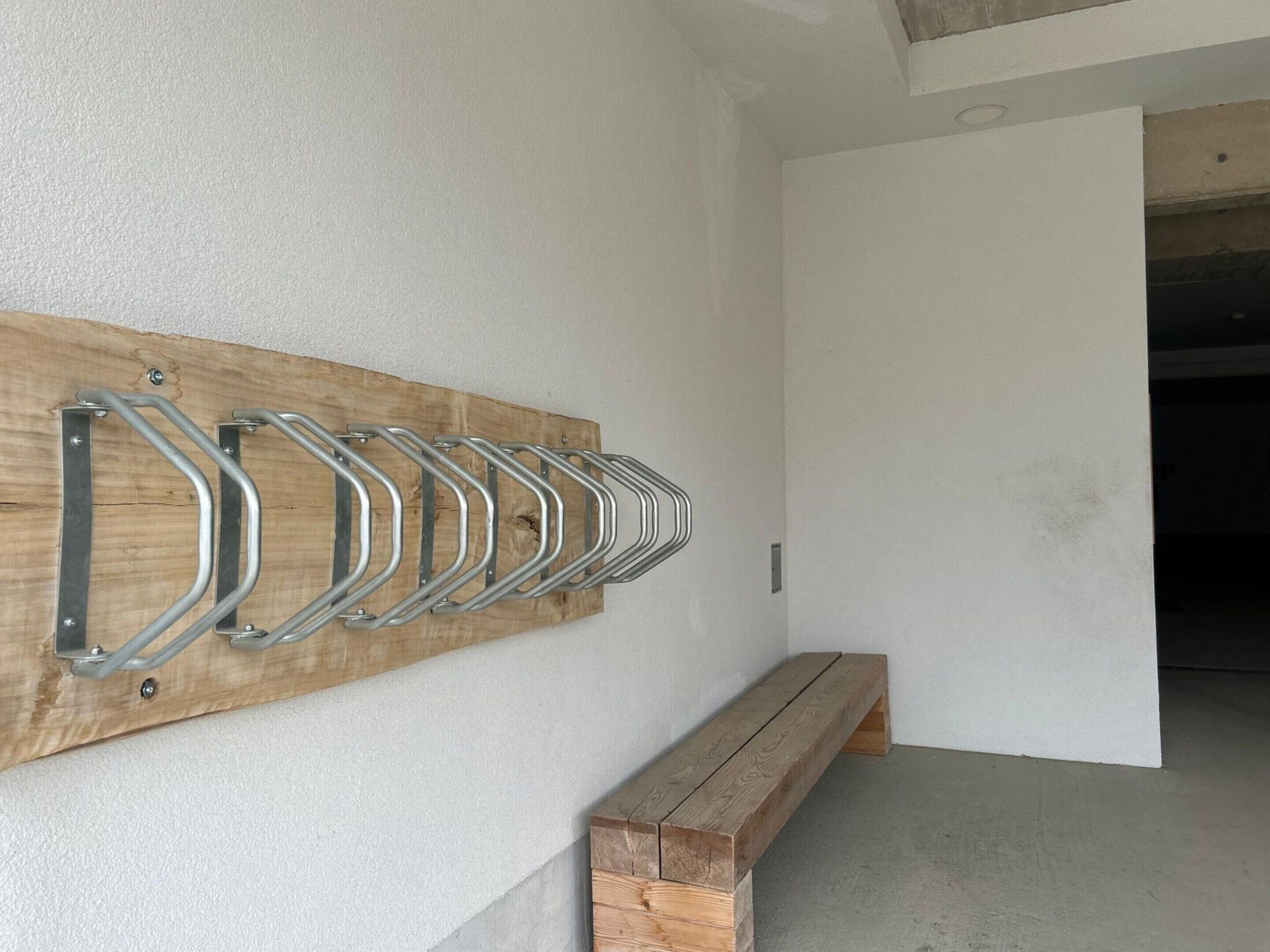 A wooden bench with metal hooks on a wall, likely for hanging items.