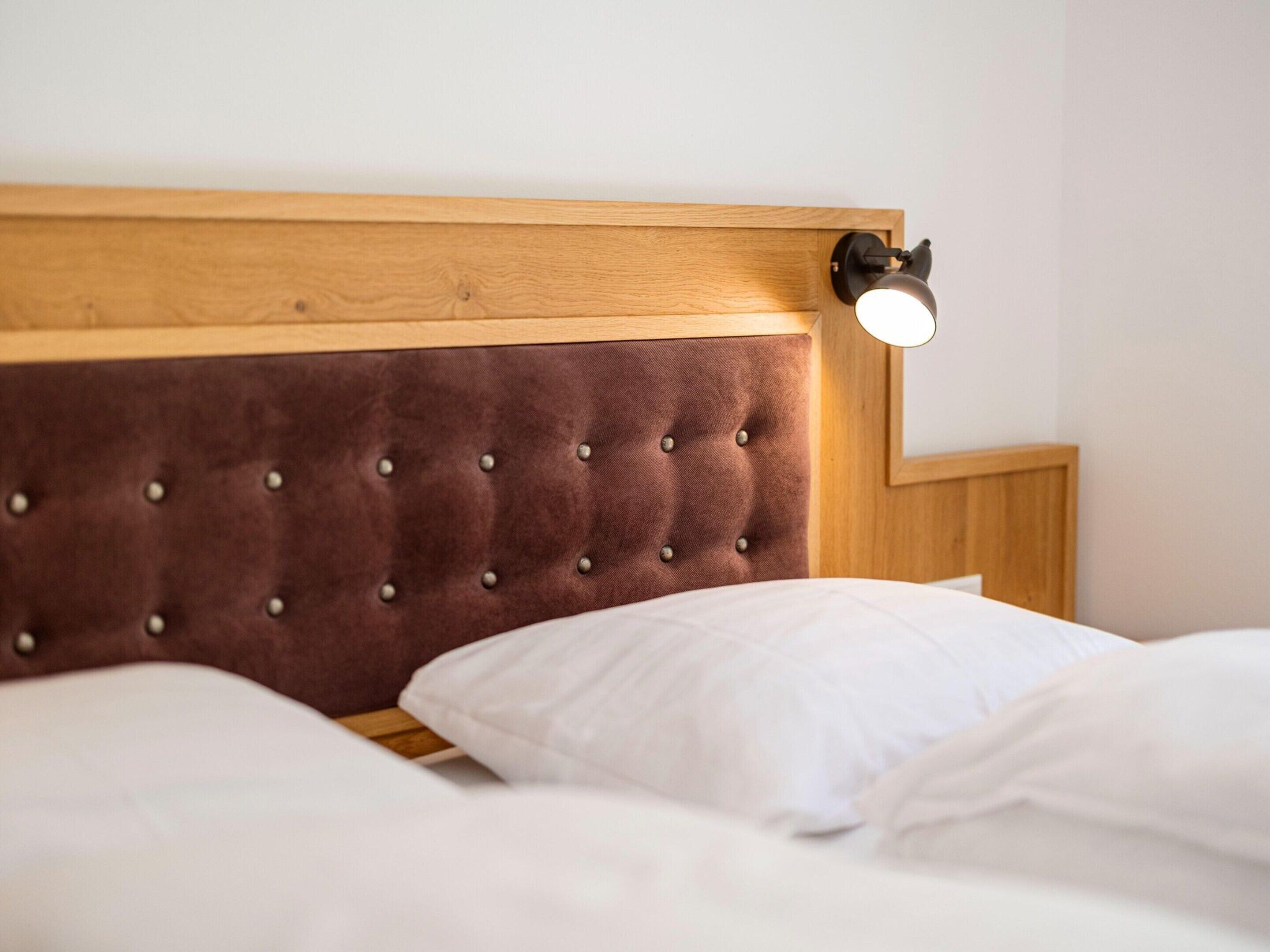 A bed with a wooden headboard and a single bedside lamp.