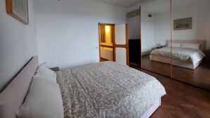 A bedroom with a bed, a mirror, and a door leading to another room. - Cozy apartment nestled in the Chianti hills 10 km from Florence (Toscana)