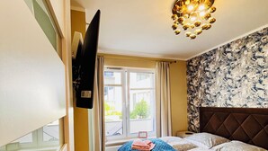 Un dormitorio con cama, televisión, ventana y candelabro.