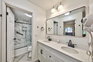 Un baño moderno con un espejo grande, dos lavamanos, una ducha y un secador de pelo sobre el mostrador.