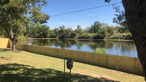 A grassy area with a wooden fence and a pond. - Treasure Bay 3-bedroom house with WiFi, fitness room in Monroe  (Monroe)