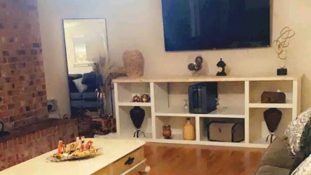 A living room with a flat-screen TV mounted on the wall, a white entertainment unit with various items, a brick wall, and a fireplace. - Treasure Bay 3-bedroom house with WiFi, fitness room in Monroe  (Monroe)