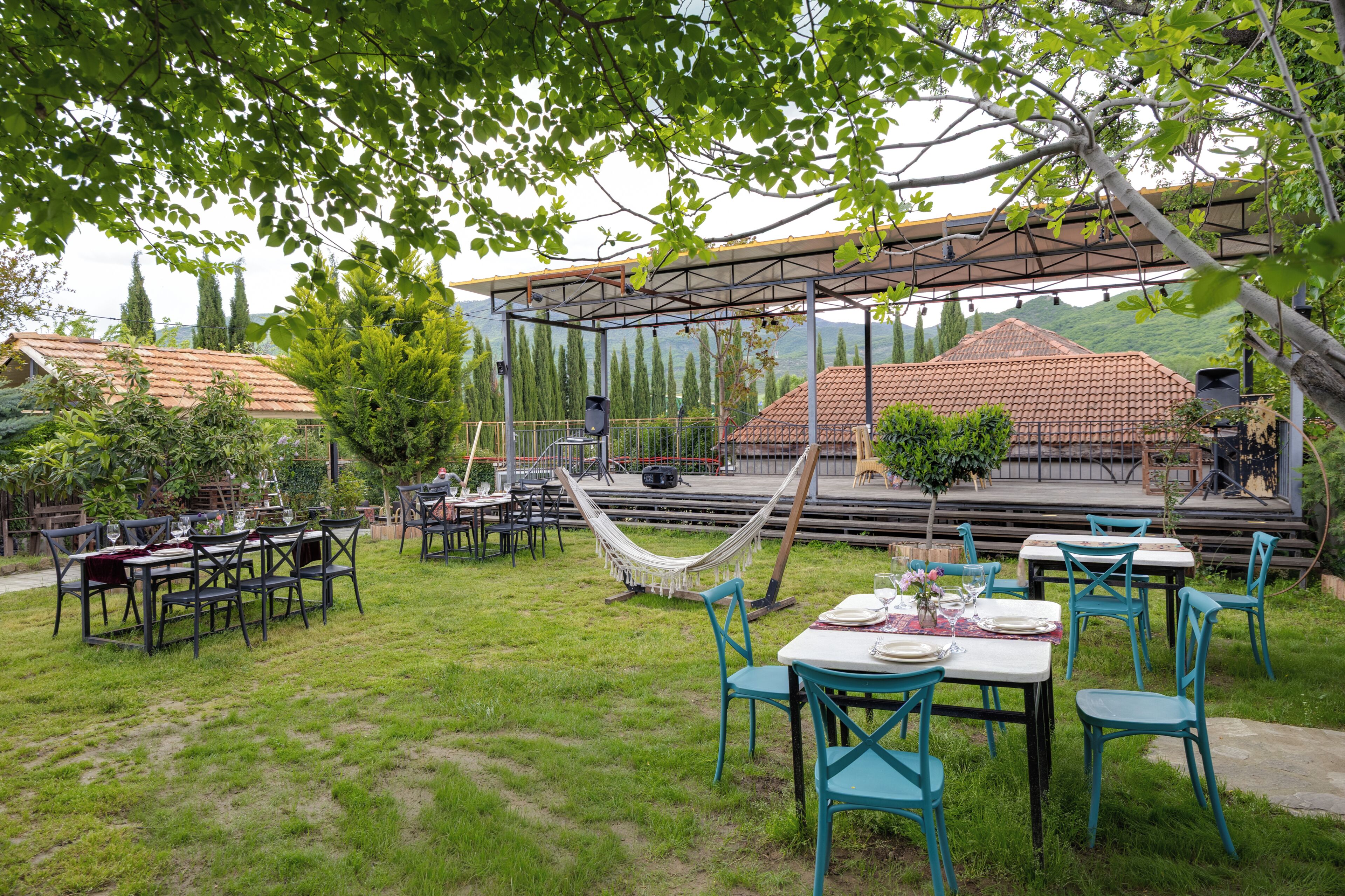 Un espace extérieur aménagé pour les repas, avec des tables et des chaises, un hamac et un coin salon abrité.