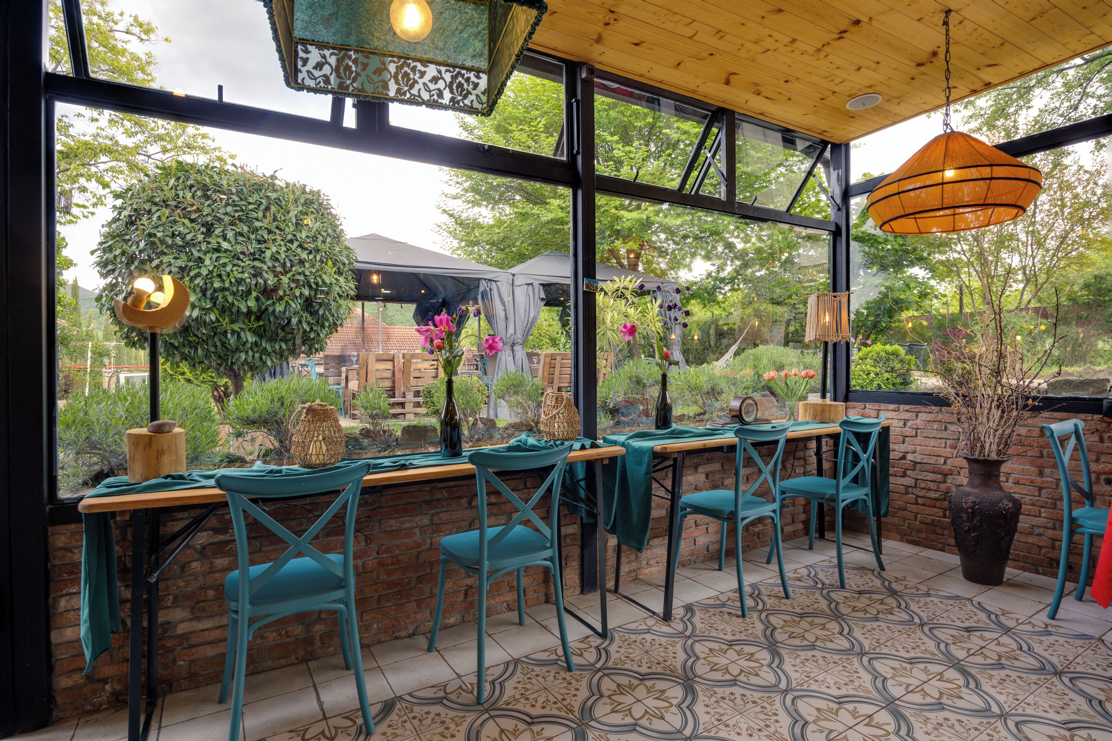 An outdoor dining area with brick walls, large windows, and a view of greenery.