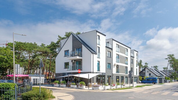 A modern multi-story hotel with balconies, outdoor seating, and a café. - Apartamenty Sun & Snow Horizon Park II (Dziwnów)