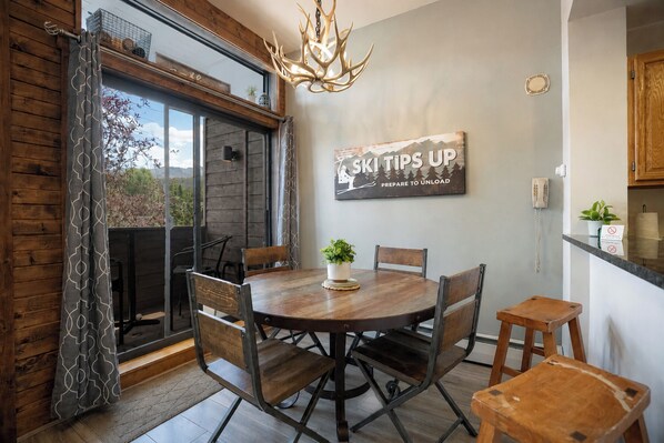 A dining area with a round table, chairs, a chandelier, and a sign on the wall.