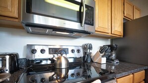 Une cuisine équipée d’un four à micro-ondes, d’une cuisinière et d’une machine à café, tous en acier inoxydable.