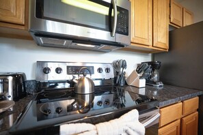 Una cocina equipada con microondas de acero inoxidable, estufa y cafetera.