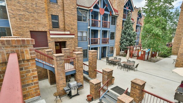A multi-story building with a brick facade, outdoor seating area, and a barbecue grill. - River Mountain Lodge Aspen Trail Condo: Ski In, Downtown Breck (Breckenridge)