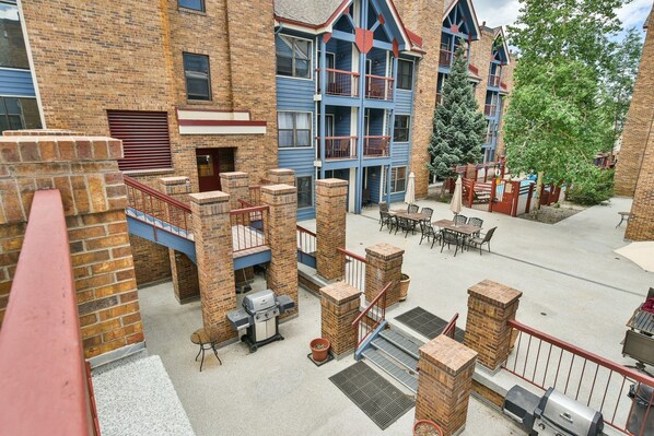 Un immeuble à plusieurs étages avec une façade en briques, un espace extérieur aménagé pour s’asseoir et un barbecue.