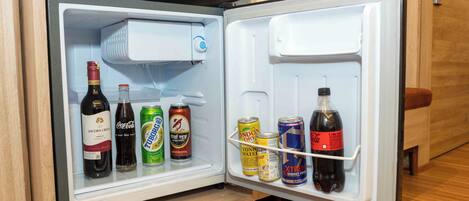 A small refrigerator with a freezer compartment on top, containing various beverages and cans.