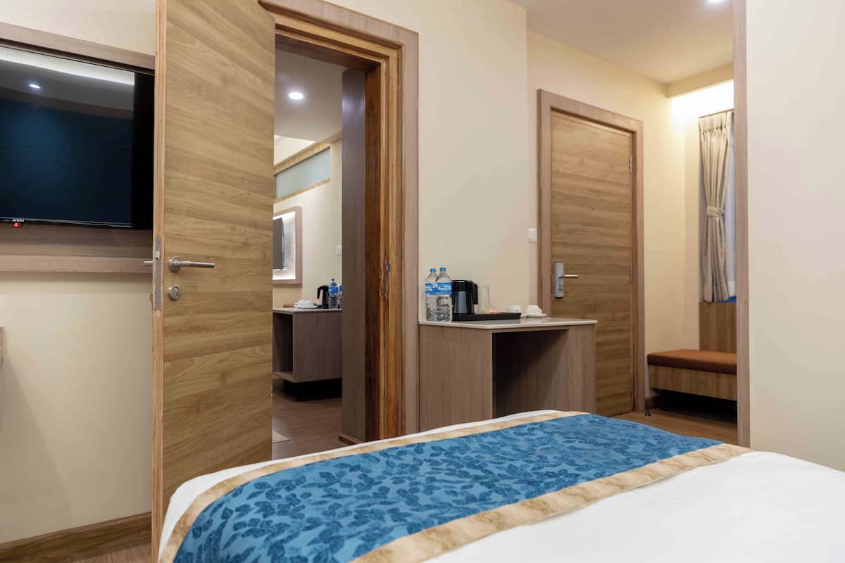A hotel room with a bed, a desk, a chair, a television, and a bathroom door.