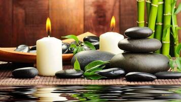 A serene spa setting with candles, stones, and bamboo.