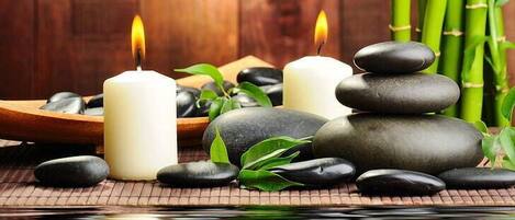 A serene spa setting with candles, stones, and bamboo.