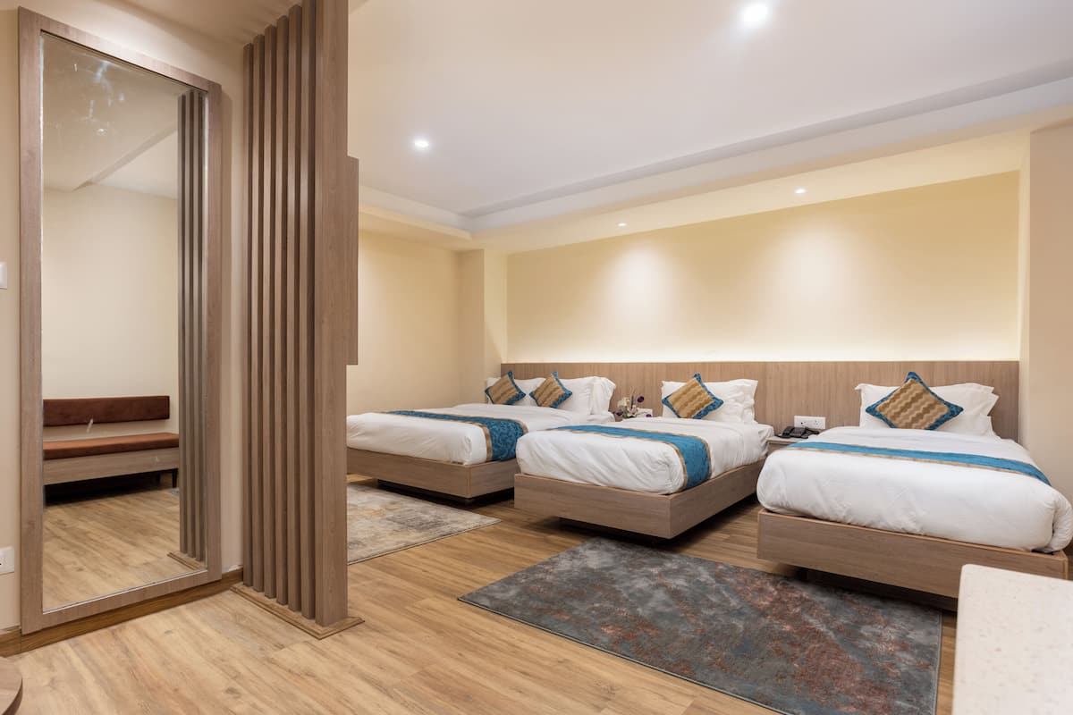 A hotel room with two beds, a bench, and a large mirror.