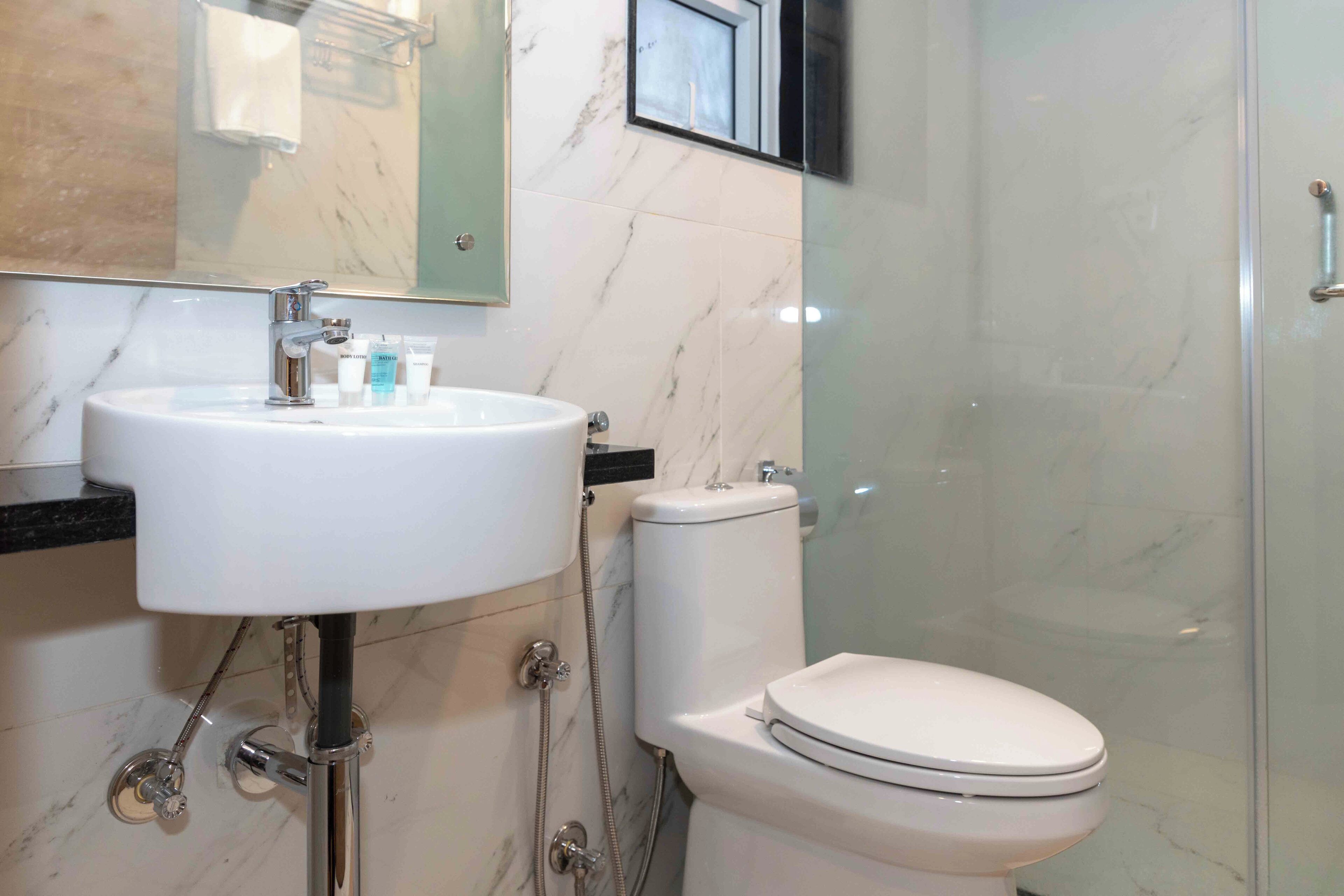 Un baño con lavamanos blanco, inodoro y cabina de ducha de vidrio.