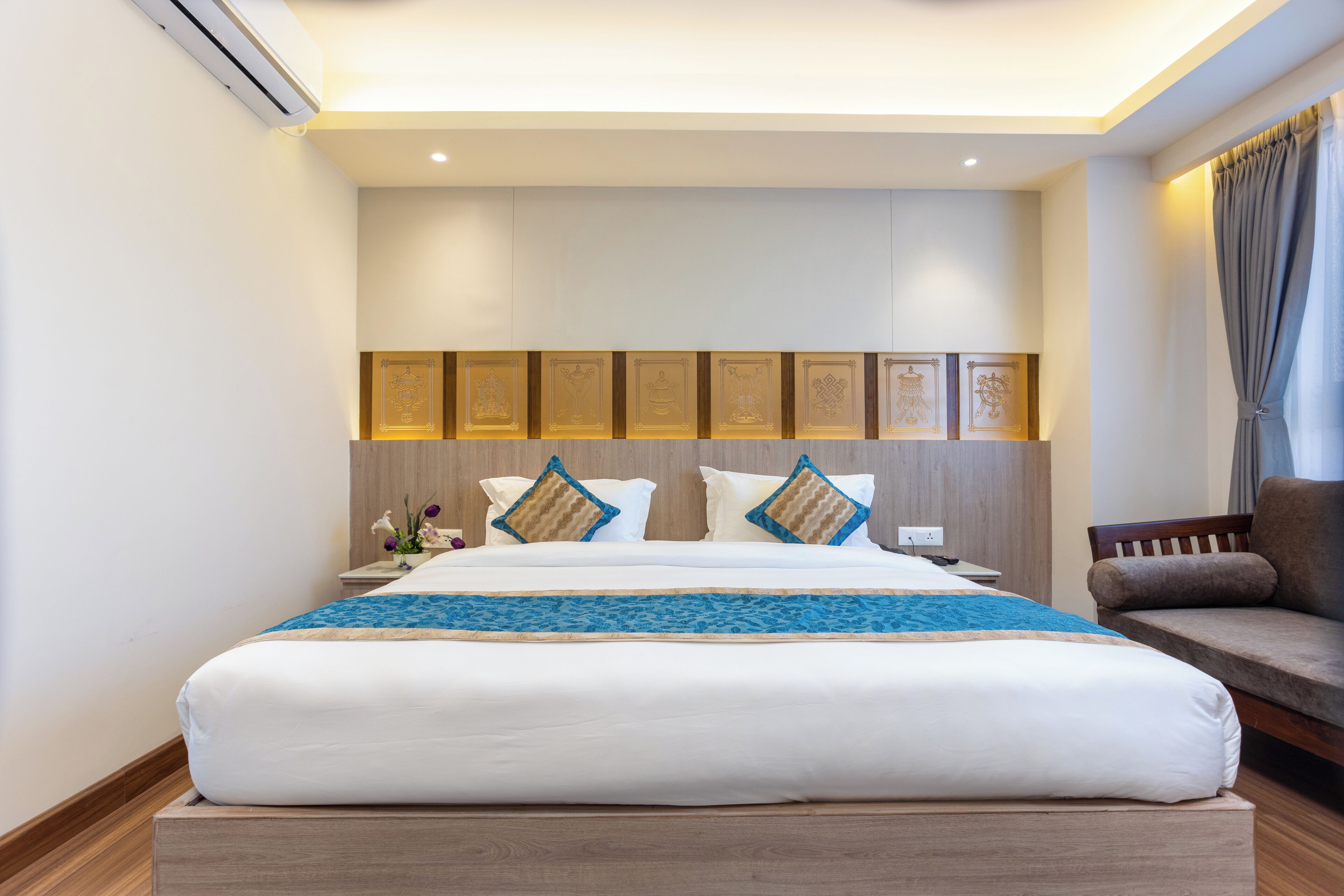Una habitación de hotel moderna con una cama grande, un cabecero de madera, un sofá y un panel decorativo en la pared.