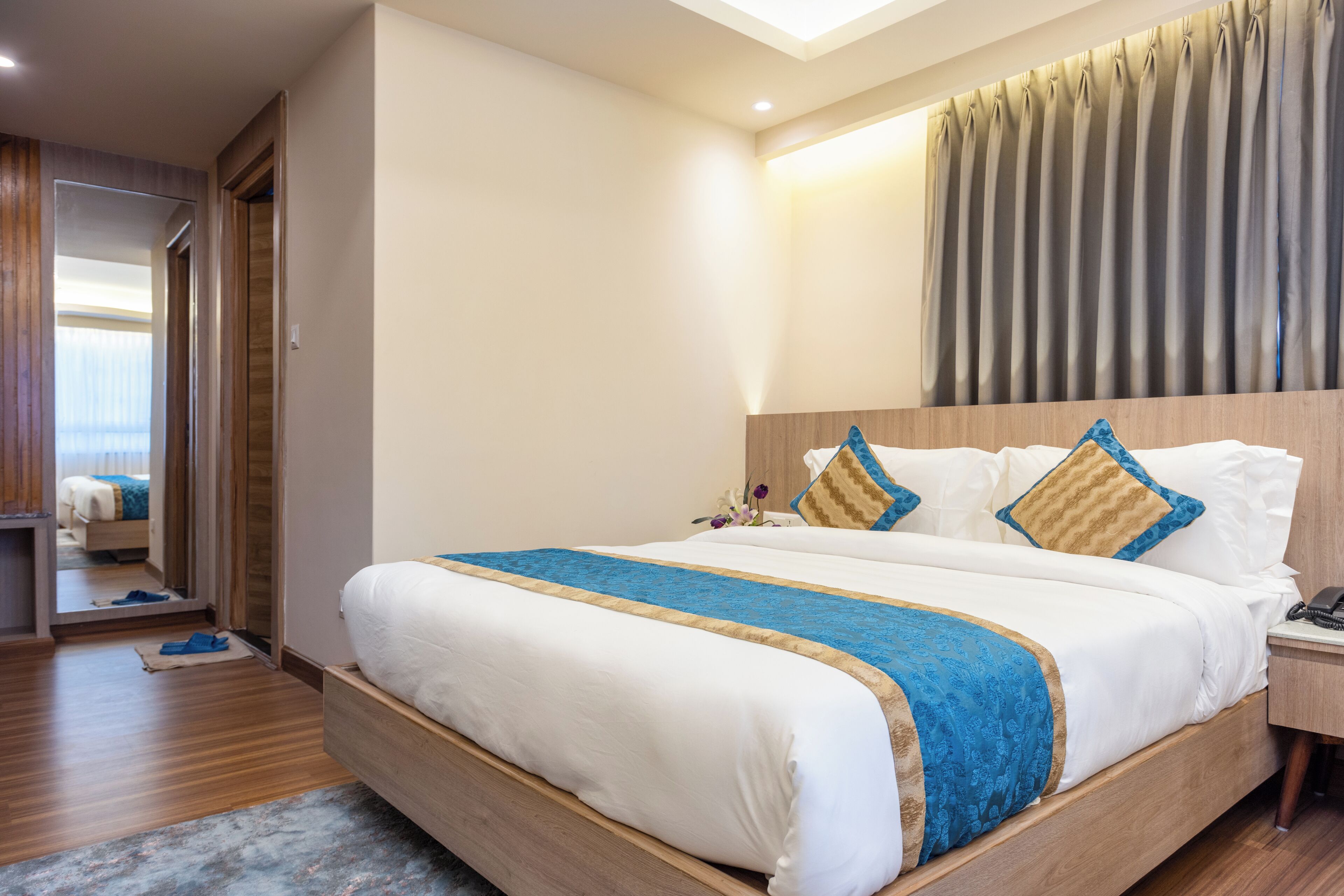 A hotel room with a large bed, wooden headboard, and a view of the city through the window.