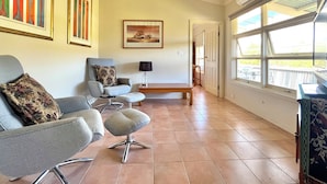 A room with grey armchairs, a bench, and a framed picture on the wall. - Self contained cabin in quiet coastal bushland setting. Pet friendly! (Robe)
