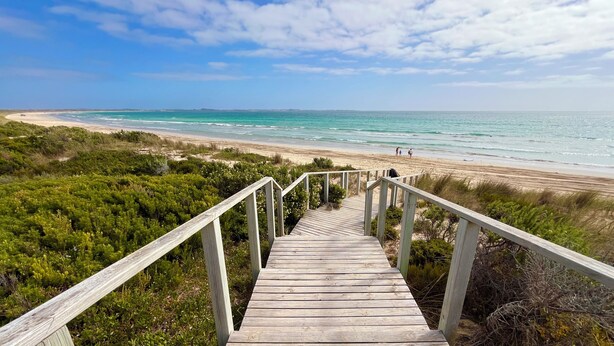 A wooden staircase leading to a beach with a clear view of the ocean and distant land. - Self contained cabin in quiet coastal bushland setting. Pet friendly! (Robe)