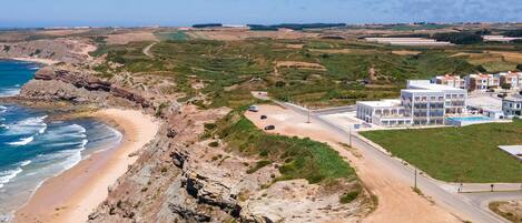 Un hôtel situé sur la côte, avec un rivage rocheux, un parking et une piscine.