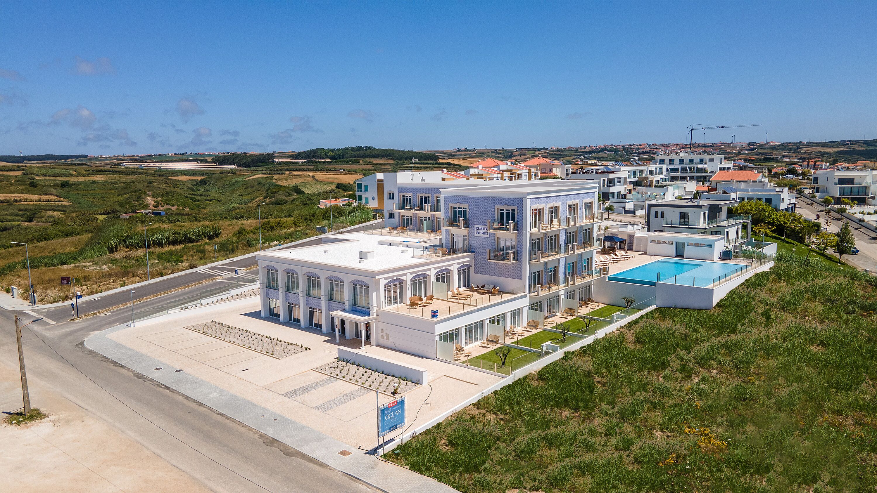 A modern hotel with multiple floors, a rooftop pool, and a view of the surrounding landscape.
