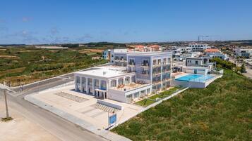 A modern hotel with multiple floors, a rooftop pool, and a view of the surrounding landscape.
