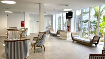 A spacious lobby with striped armchairs, a sofa, and a reception desk.