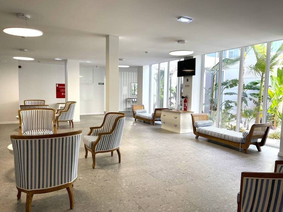 A spacious lobby with striped armchairs, a sofa, and a reception desk.