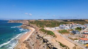 A coastal town with modern buildings, a beach, and rocky cliffs. - Ocean View Apartments - Ocean View (Lourinha)