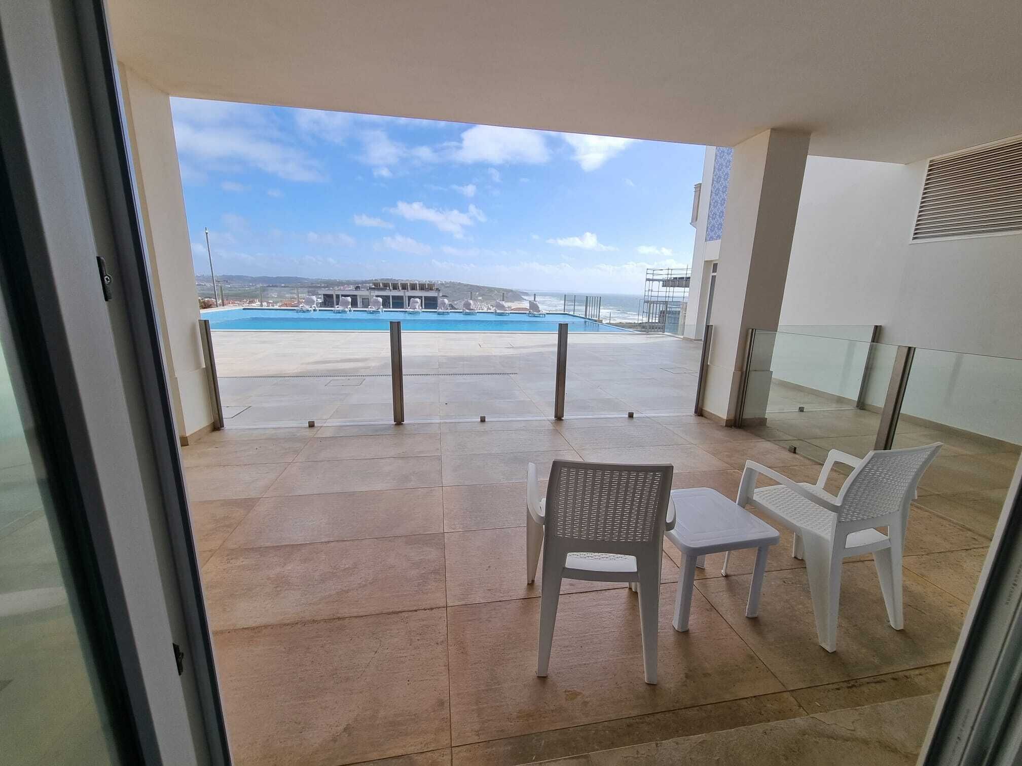 Un balcón con vista a una piscina y la playa.